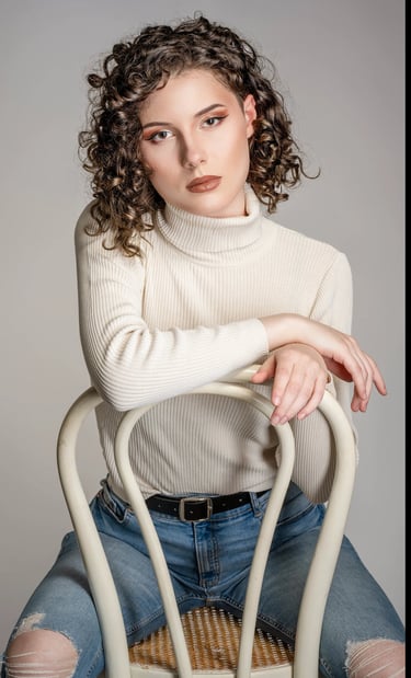 Porträt einer jungen Frau mit lockigem Haar, hellem Rollkragenpullover und Jeans, aufgenommen im Studio von LensAndLook – mod