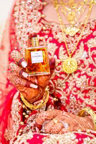 detail photo of bride holding Chanel no5 perfume, bride's traditional red dress is the backdrop