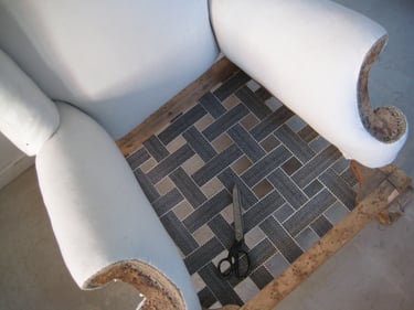 Antique armchair with scroll arms being upholstered with traditional techniques. Features webbed seat and calico arms