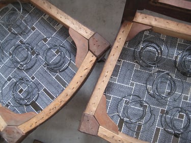 Pair of antique dining chairs being upholstered. Springs are being fitted to new seat webbing