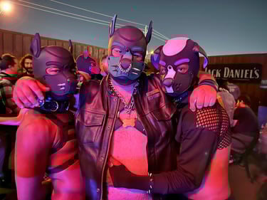 Three men posing in pup masks outdoors at a night bar event.