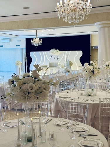 Elegante salón de baile de recepción de boda con centros de mesa florales blancos, candelabros de c