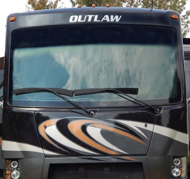 Front view of a Thor Outlaw Class A motorhome featuring a large windshield with cloud reflections.