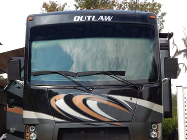 Front view of a Thor Outlaw toy hauler motorhome with custom graphics and large panoramic windshield.