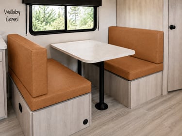 Modern RV booth dinette with camel-colored faux leather cushions and a white stone-top table.