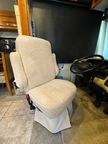 Plush beige sheepskin seat cover installed on a swivel captain chair inside a luxury motorhome RV.