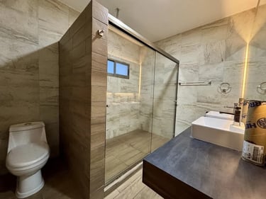 Imagen de remodelación de baño con recubrimientos de mármol, cancel de cristal y muebles de baño modernos