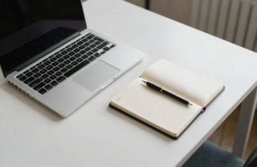 A top-down view of a minimalist desk with a silver laptop and notepad in a North American / US city apartment.