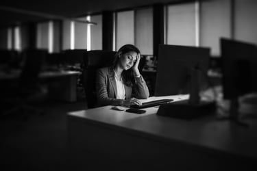 woman feeling tired at a desk working alone in an empty office