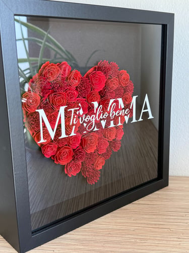 quadro nero realizzato a mano con un cuore rosso composto da fiori di carta realizzati a mano, sul vetro una scritta bianca 