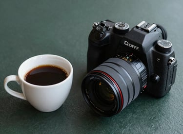 Freshly brewed coffee and a digital camera on a dark slate green surface, professional agency vibe.