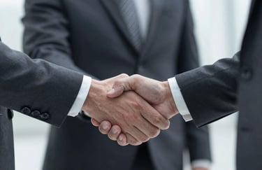 A firm handshake between two business professionals in tailored suits, focused on the connection, lighting highlighting trust.