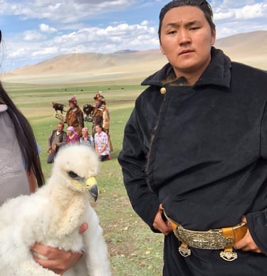 Mongolian eagle hunter with a baby eaglet on the steppe