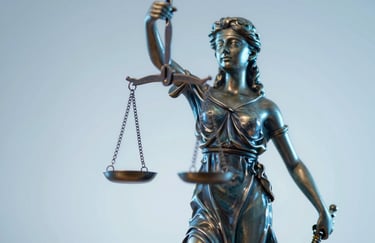 A close-up of a scales of justice statue, rendered in a modern metallic finish with #87A0B8 and #2B4A6A lighting accents.