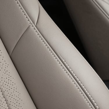 Macro shot of a high-end car&amp;amp;amp;#x27;s leather upholstery with intricate white stitching, symbolizing luxury quality and attention to detail in a North American &amp;amp;amp;#x2F; US context.