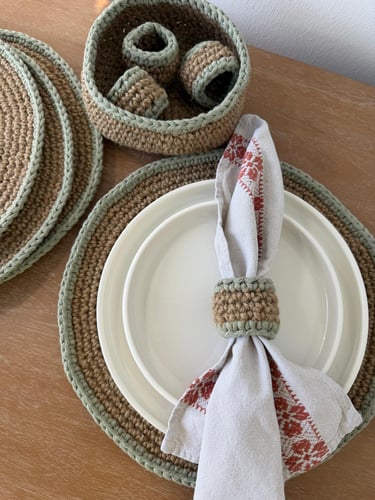 Handmade crochet jute placemats and napkin rings on a rustic dining table.