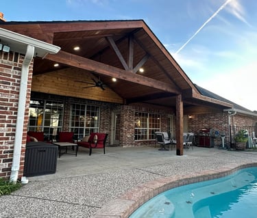 Covered patio with vaulted wood ceiling by pool.