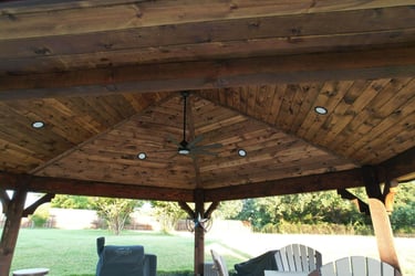Wooden gazebo ceiling with fan and recessed lighting.