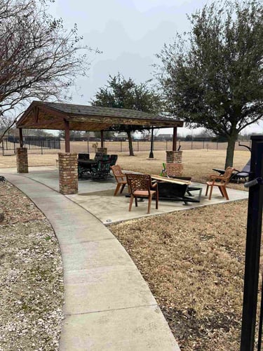 Outdoor pavilion with wood roof and patio furniture.