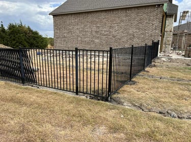 Black metal fence installed beside brick house.