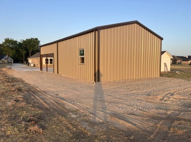New tan metal shed with gravel driveway.