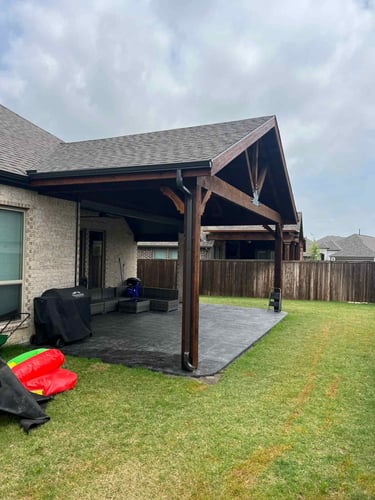 Covered backyard patio with dark wood posts.