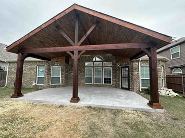 Covered patio with stained wood gable roof and concrete slab.