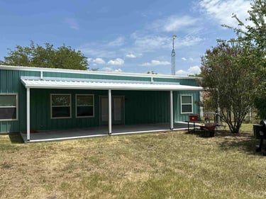 Green metal building with white metal patio cover.