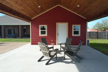 Covered patio with red shed and chairs.