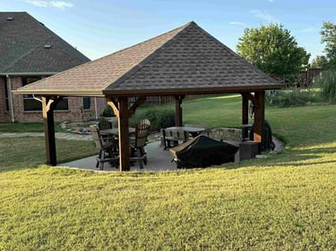 Backyard pavilion with seating and grill.