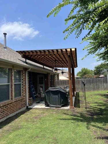 Wood pergola attached to brick house.