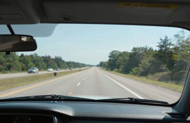 An interior shot through a perfectly clear, brand-new windshield showing a sharp, focused view of a North American road ahead, clean and bright composition.
