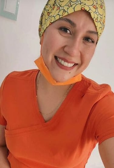 Trabajadora de la salud sonriente que viste uniforme médico naranja y un gorro quirúrgico con patito