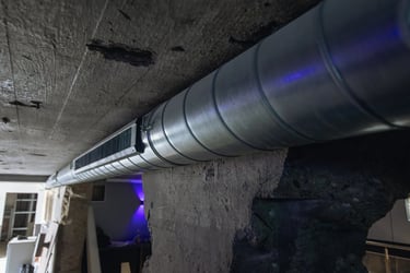 Industrial spiral ductwork and ventilation system installed against a concrete ceiling in a building.