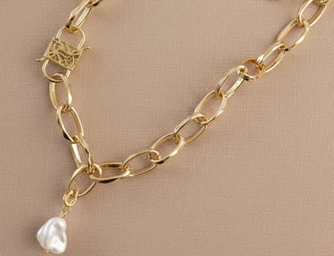 Collar de eslabones gruesos dorados con un dije de cuarzo blanco y un cierre de candado ornamentado