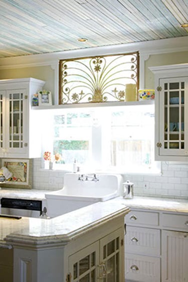 Shabby chic kitchen with white farmhouse sink, subway tile backsplash, and ornate gold window gate.
