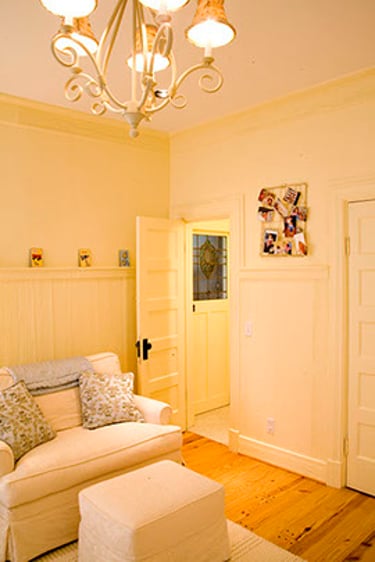 Cozy bedroom corner with a white armchair, ottoman, and elegant chandelier lighting.
