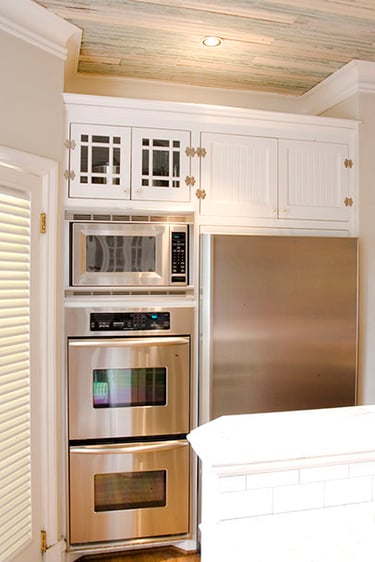Modern kitchen featuring stainless steel double wall ovens, built-in microwave, and white cabinetry.