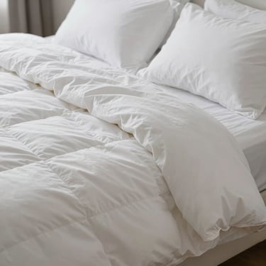 A close-up shot of thick, fluffy white blankets and pillows freshly laundered, North American / US bedroom setting, soft daylight, focusing on comfort and cleanliness.