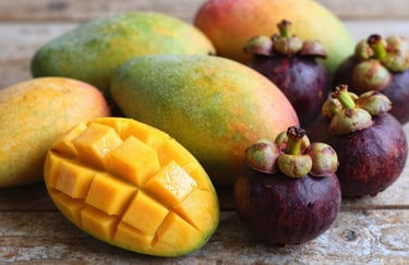 A vibrant display of fresh Nam Dok Mai mangoes and mangosteens on a rustic wooden surface, highlighting tropical freshness and natural colors.