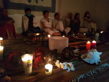 Altar prehispánico ceremonial con velas, flores, cuencos tibetanos y de cuarzo al centro de un grupo de personas en Oaxaca