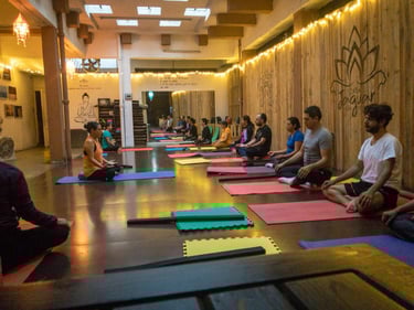 Grupo de personas practicando meditación en estudio de yoga cálido y bien iluminado en Ajna Oaxaca.