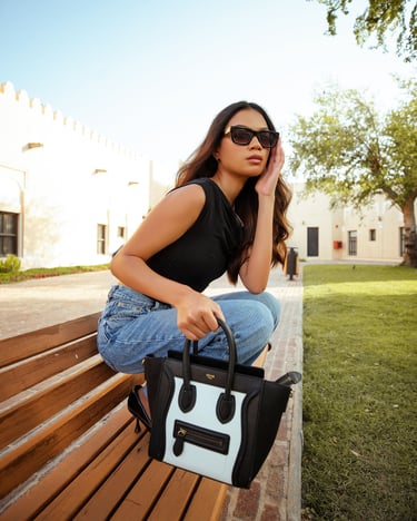 Jeune fille qui tient un sac Céline posé sur un banc
