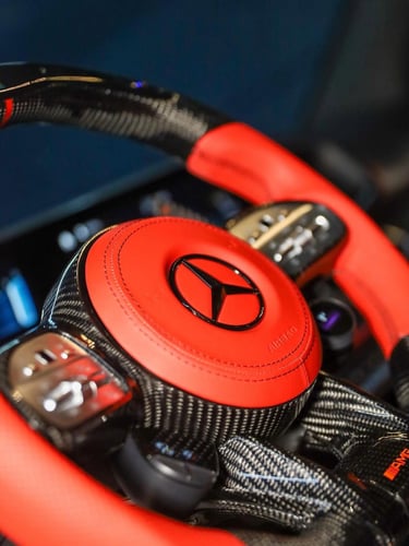 Luxury Mercedes-Benz AMG carbon fiber steering wheel with red leather trim and black logo.