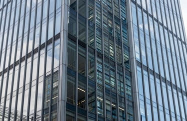 An architectural photography shot of a modern glass building facade in a North American business district, highlighting clean lines, transparency, and a professional, forward-thinking aesthetic.