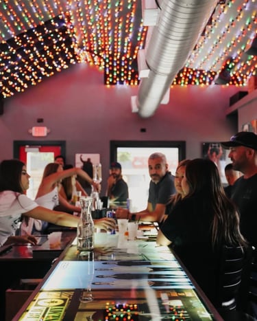 Friends gathered at a sports bar with colorful ceiling lights and a glowing digital countertop.
