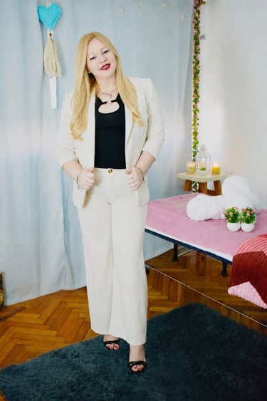 Atenea, masajista profesional con traje blanco, posando junto a la camilla en su gabinete de Almagro.