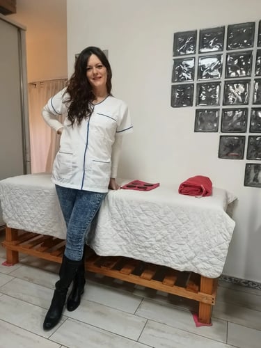 Tirzha masajes en Flores, posando de pie junto a la camilla en su espacio de relax privado.