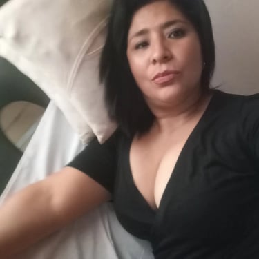 Rosa masajes Ituzaingó, selfie recostada luciendo blusa negra escotada.