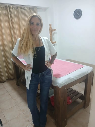 Ailyn, masajista profesional posando de pie junto a su camilla en su gabinete de masajes en Microcentro.